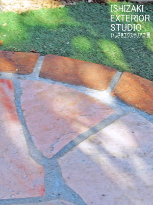ピンク系の乱形石材と縁取りレンガのアプローチ